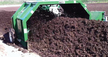 A large compost pile being mechanically turned