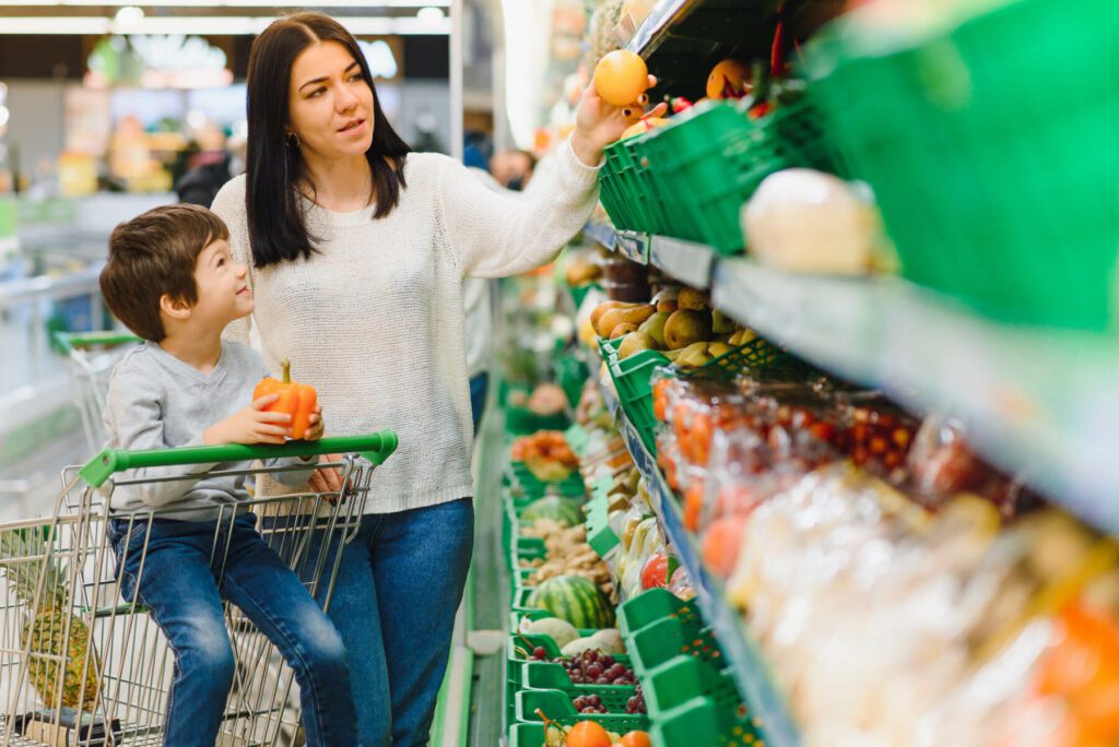 A mother and her son picking out fresh produce at a grocery store. this article discusses the effects of healthy, nutrient dense soil on the produce consumers eat.