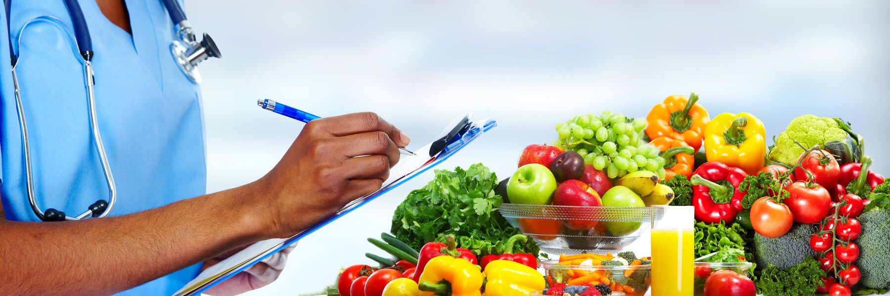 A doctor's hand writing a prescription of fresh fruits and vegetables with colorful produce in front of them to promote human health