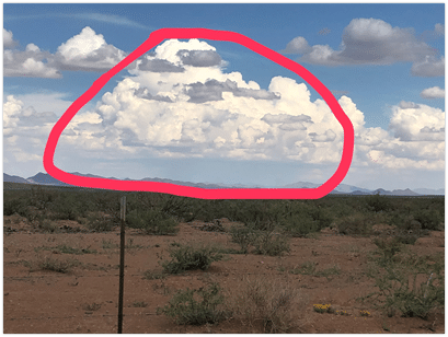 Storm clouds forming above the Las Damas ranch while there are few clouds over the rest of the area. The large storm area is outlined in red above the ground