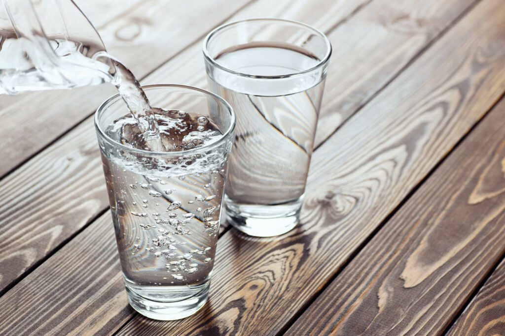 clean drinking water being poured into two glasses on a table