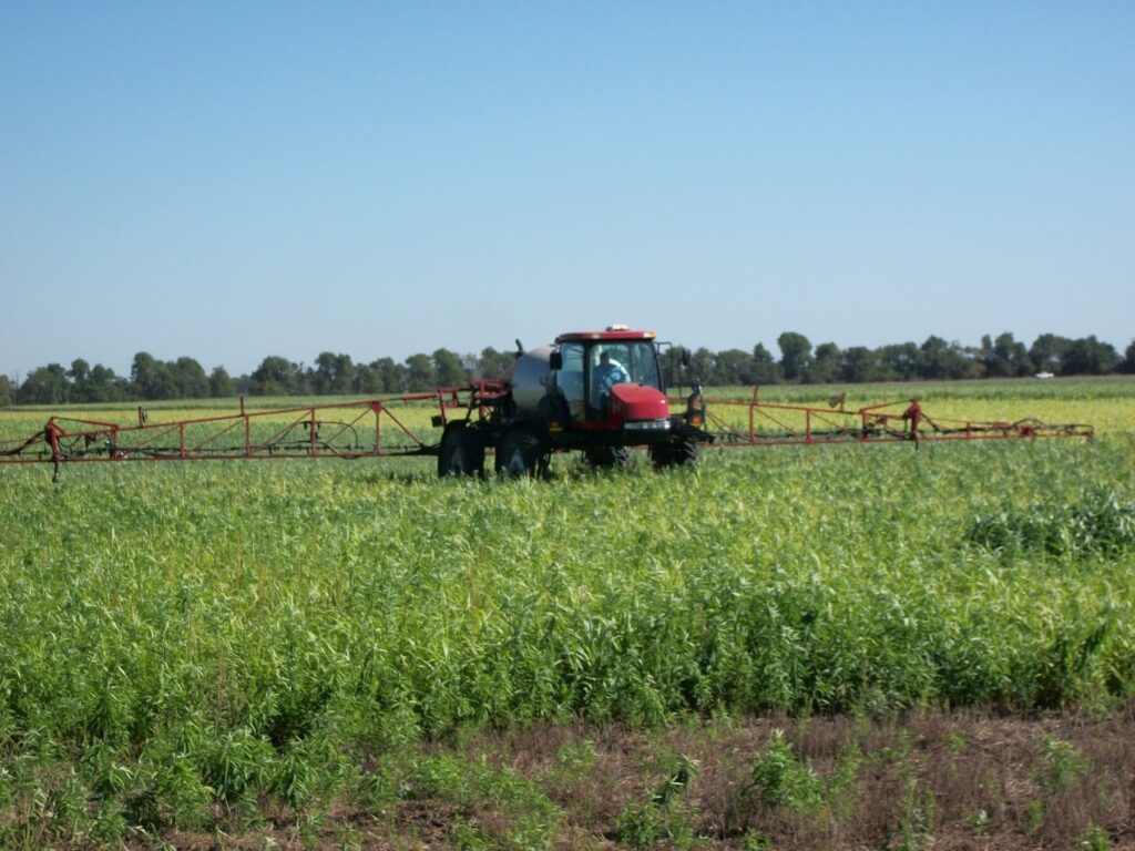 red tractor spraying herbicide on a cover crop